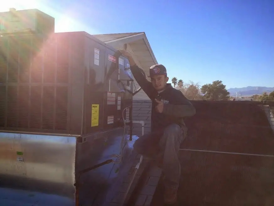 HVAC technician performing AC Tune-Up on a rooftop unit in Harrison